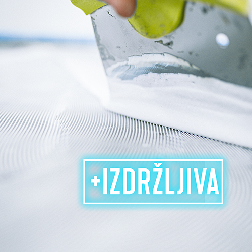 Krupni plan ruke koja špahtlom nanosi bijelo ljepilo ili žbuku na površinu. Riječ +IZDRŽLJIVA napisana podebljanim plavim slovima nalazi se u svjetlećem okviru.